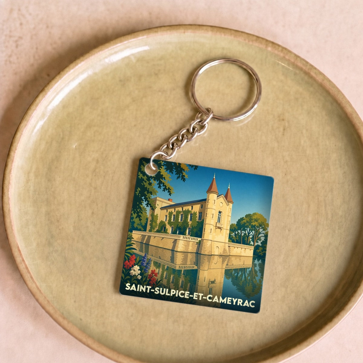 Porte-clés souvenir de la ville de Saint-Sulpice-et-Cameyrac avec une illustration stylisée d'un château se reflétant dans l'eau.