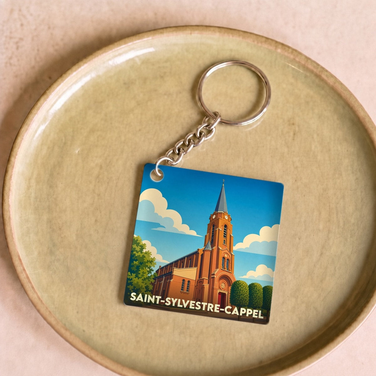 Porte-clés souvenir de la ville de Saint-Sylvestre-Cappel avec une illustration stylisée de son église.