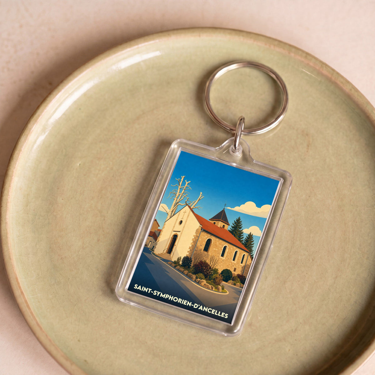 Porte-clés souvenir de la ville de Saint-Symphorien-d'Ancelles avec une illustration stylisée de son église.