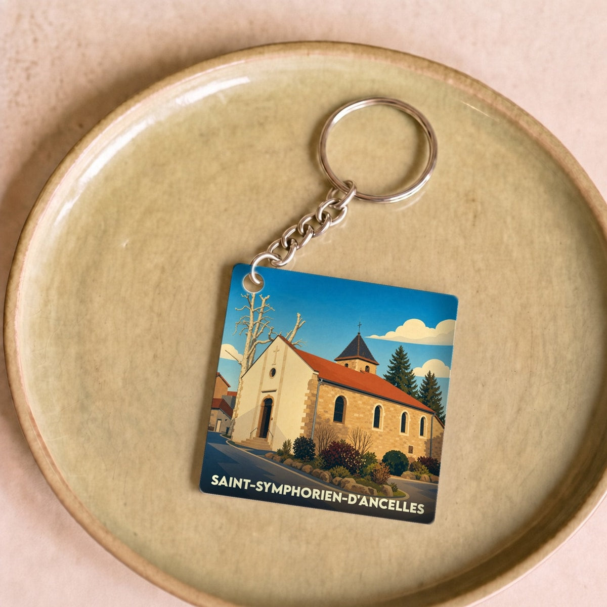 Porte-clés souvenir de la ville de Saint-Symphorien-d'Ancelles avec une illustration stylisée de son église.