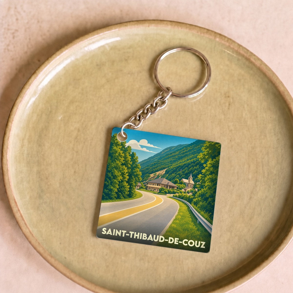 Porte-clés souvenir de la ville de Saint-Thibaud-de-Couz avec une illustration stylisée d'un paysage montagneux.