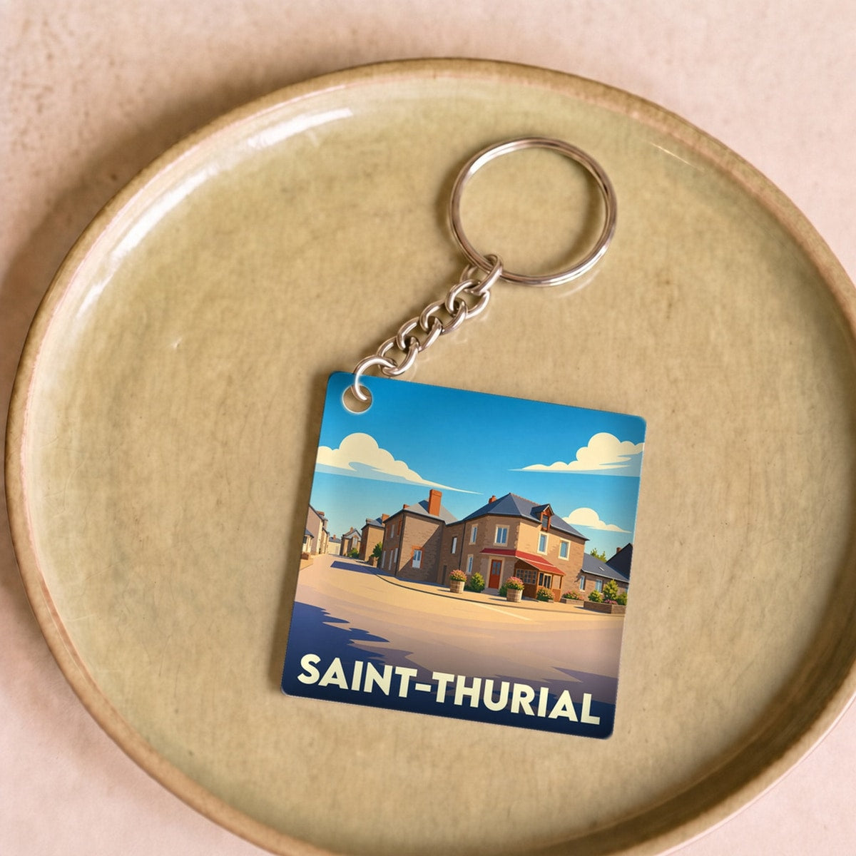 Porte-clés souvenir de la ville de Saint-Thurial avec une illustration stylisée.