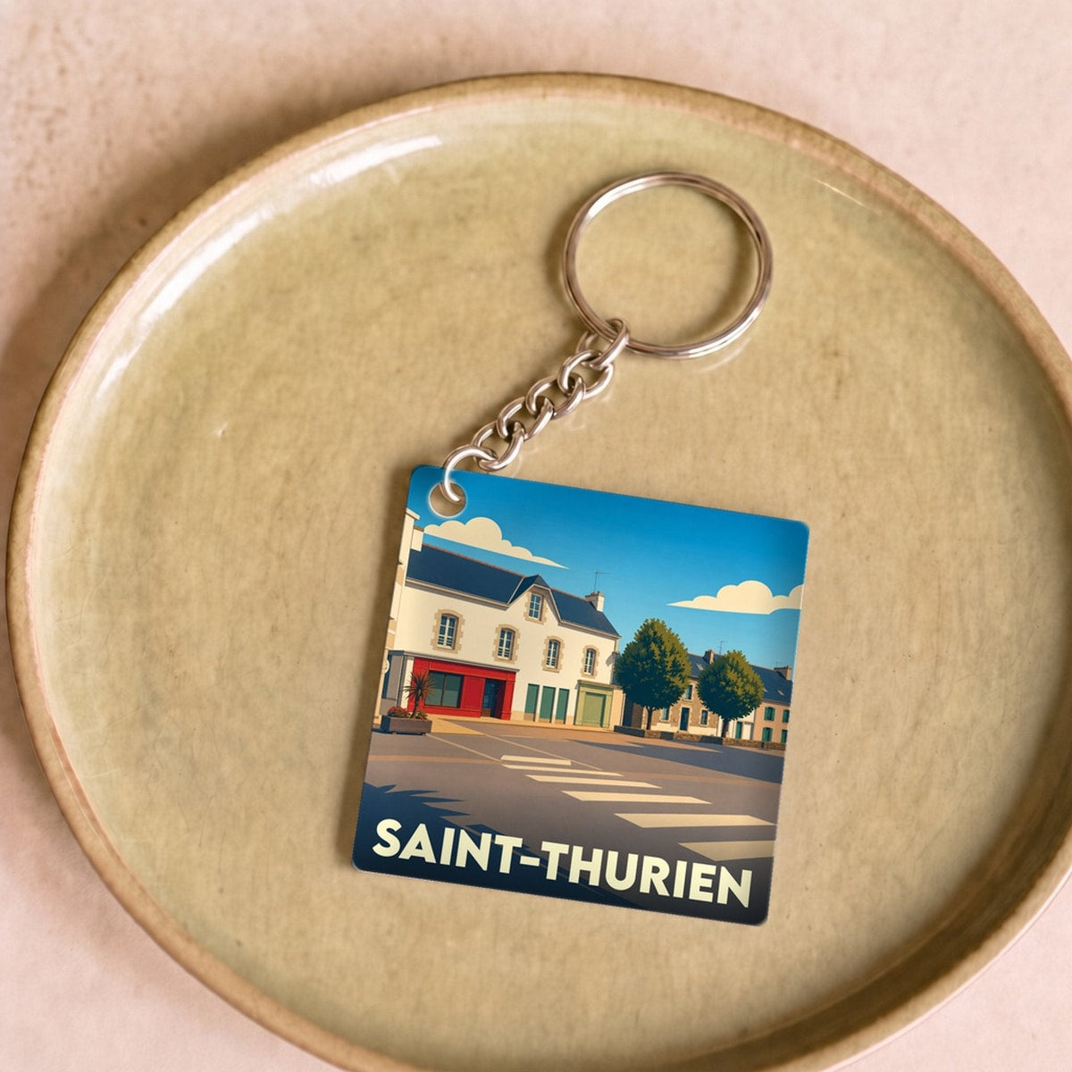 Porte-clés souvenir de la ville de Saint-Thurien avec une illustration stylisée.