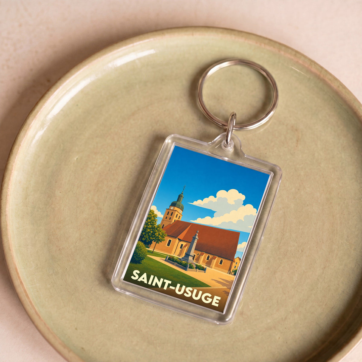 Porte-clés souvenir de la ville de Saint-Usuge avec une illustration stylisée.
