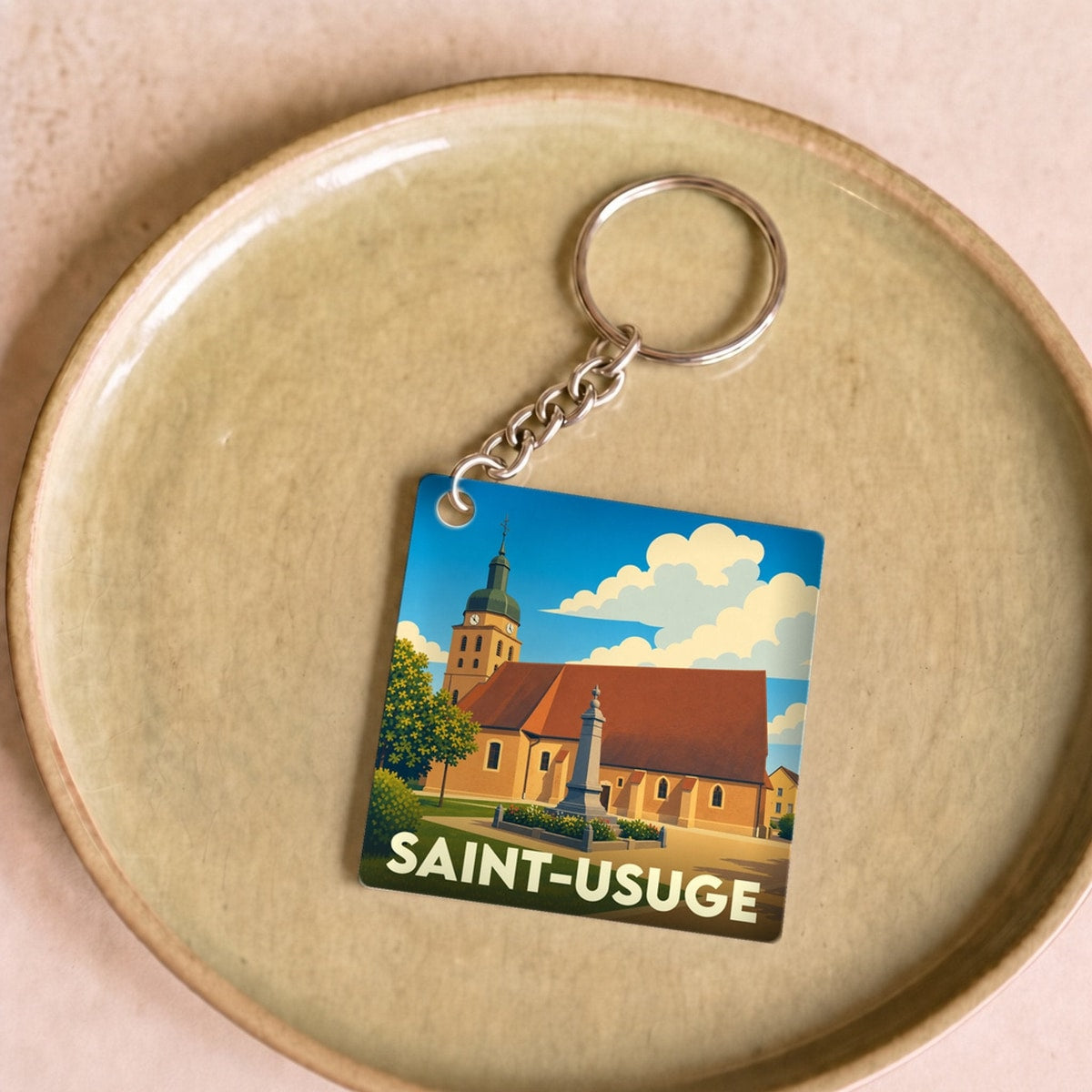 Porte-clés souvenir de la ville de Saint-Usuge avec une illustration stylisée.
