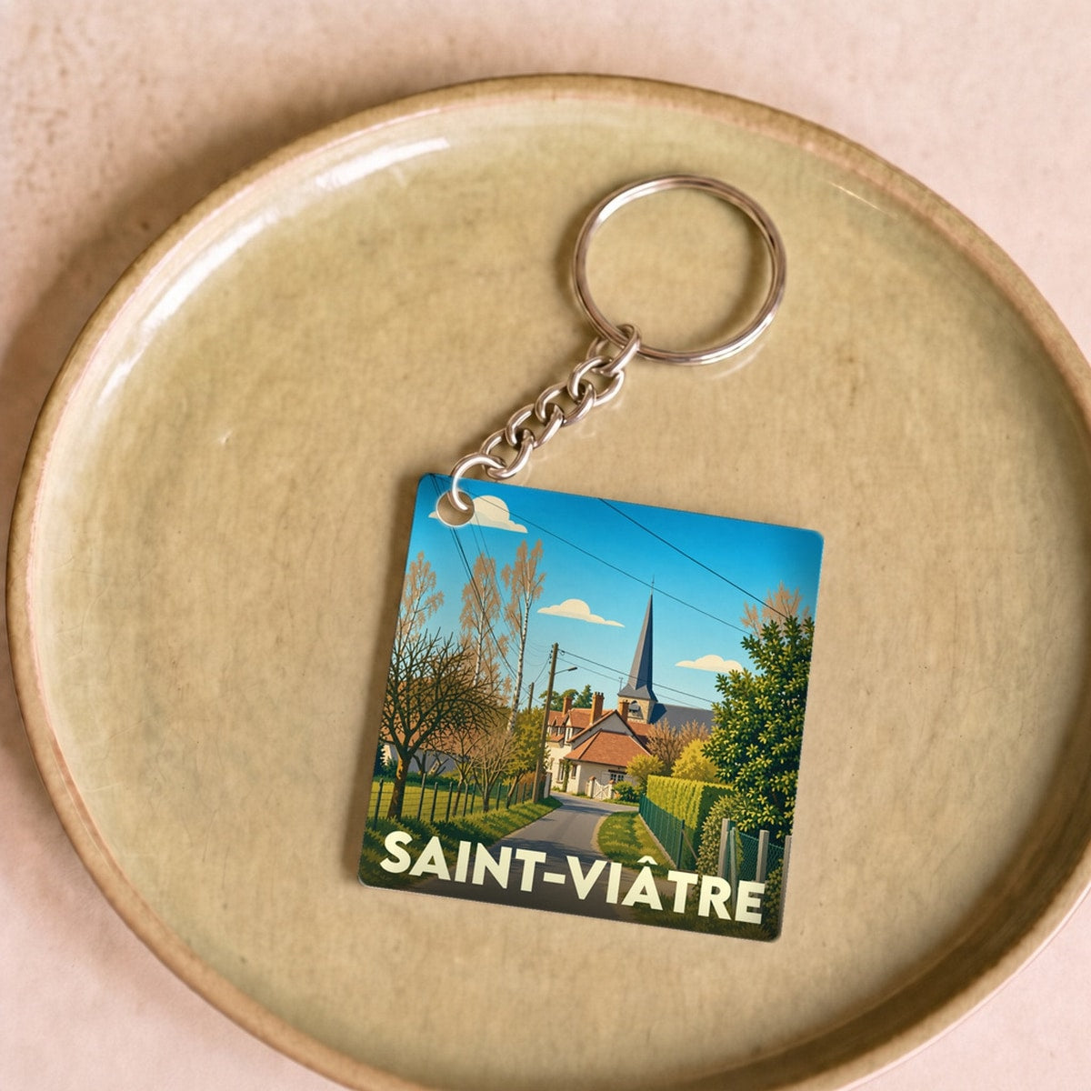Porte-clés souvenir de la ville de Saint-Viâtre avec une illustration stylisée d'un paysage de village.