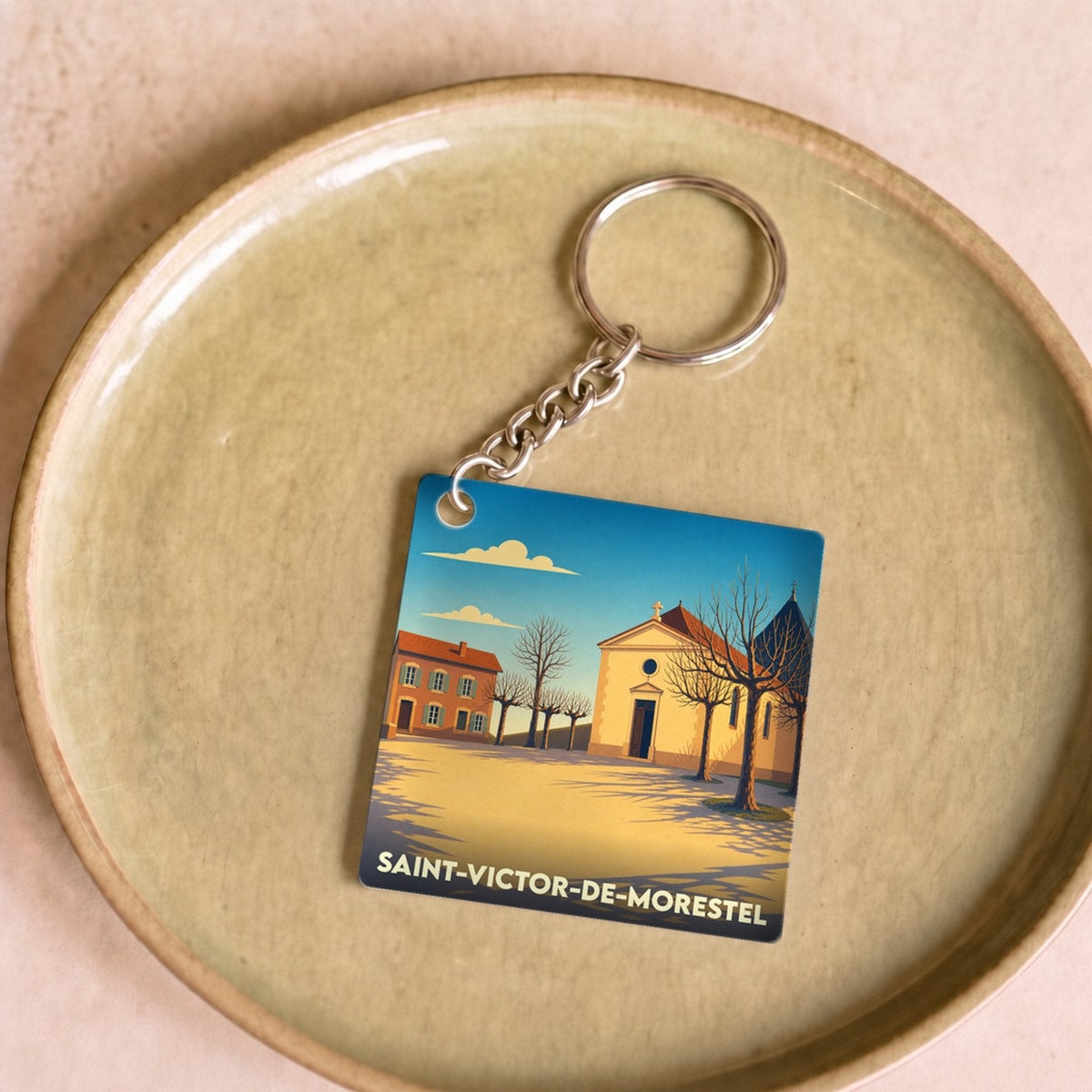 Porte-clés souvenir de la ville de Saint-Victor-de-Morestel avec une illustration stylisée.