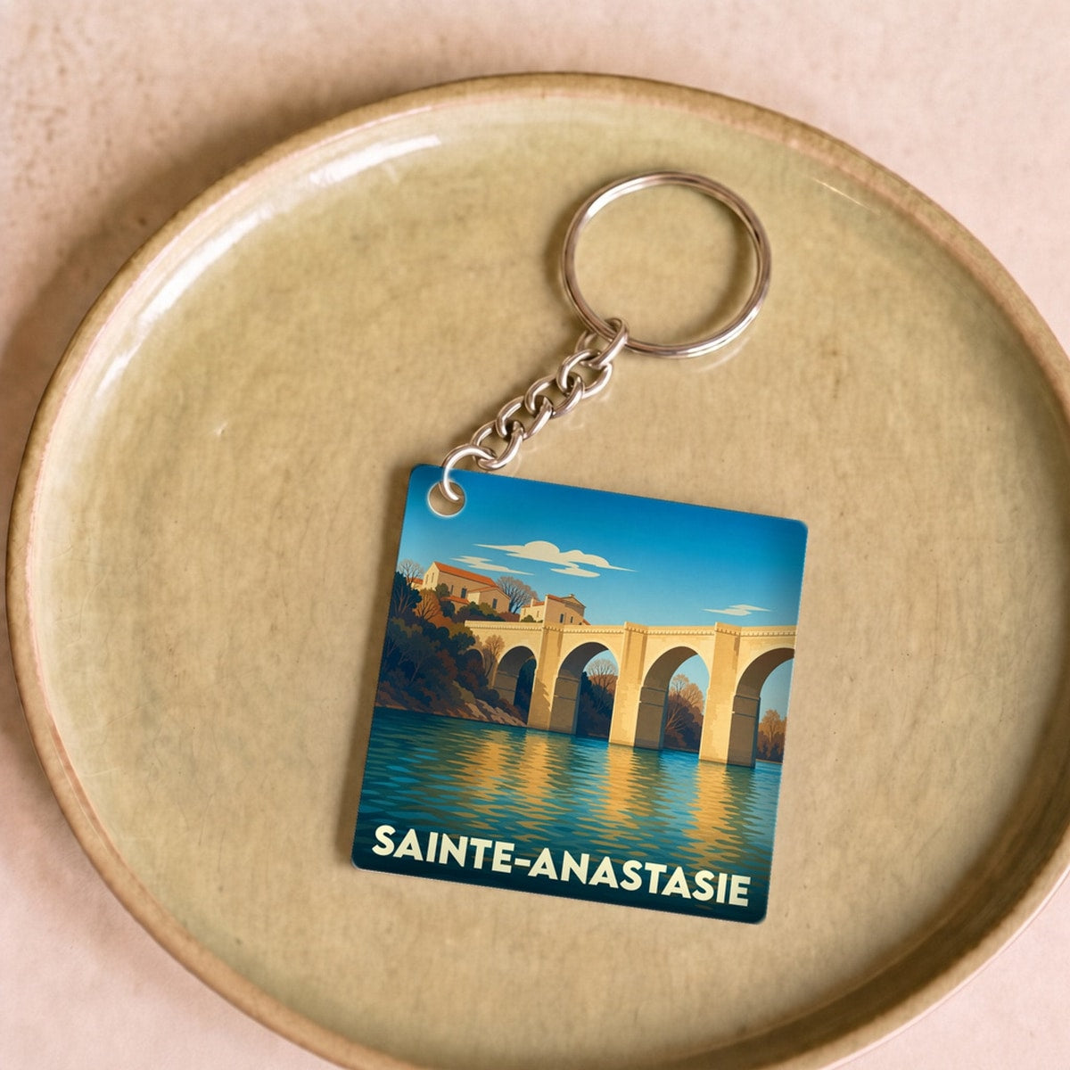 Porte-clés souvenir de la ville de Sainte-Anastasie avec une illustration stylisée d'un pont de pierre.