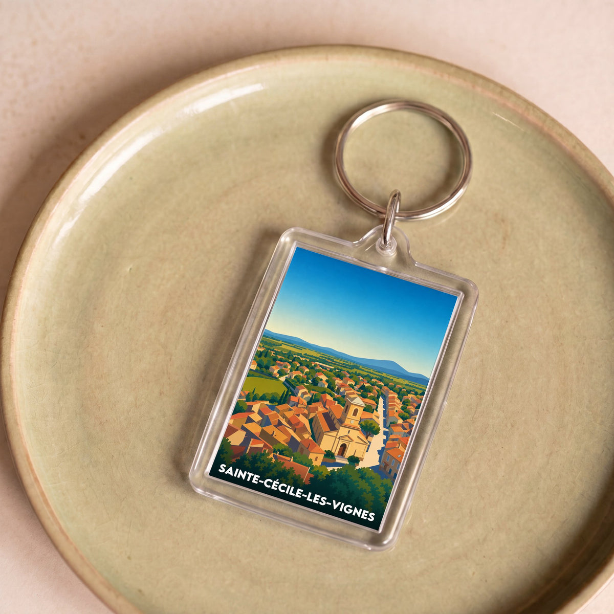 Porte-clés souvenir de la ville de Sainte-Cécile-les-Vignes avec une illustration colorée du village.
