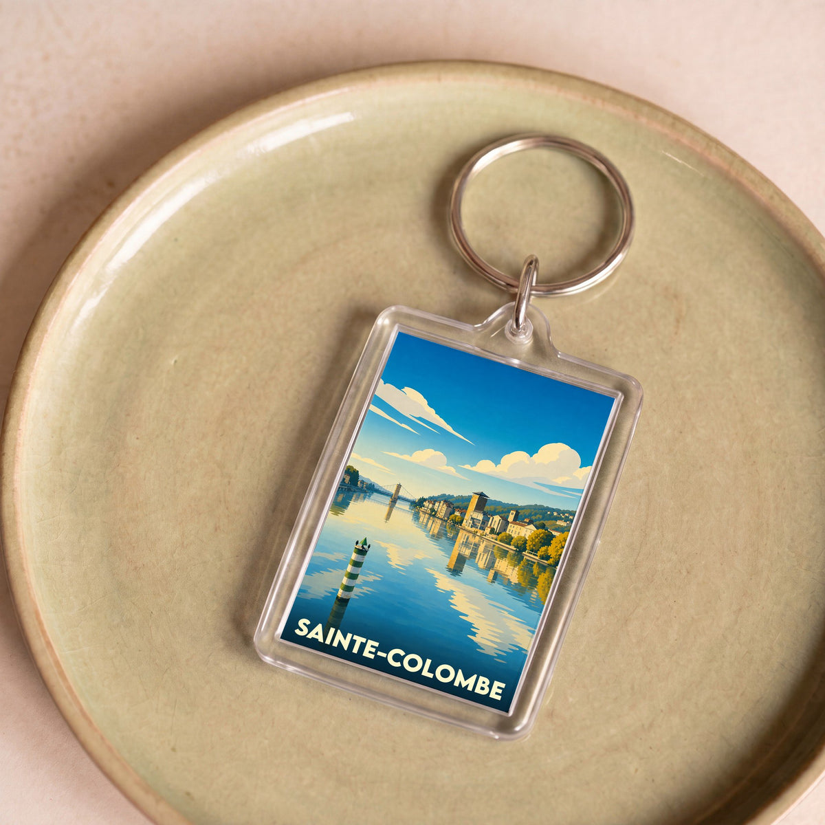 Porte-clés souvenir de la ville de Sainte-Colombe avec une illustration stylisée d'un paysage fluvial.