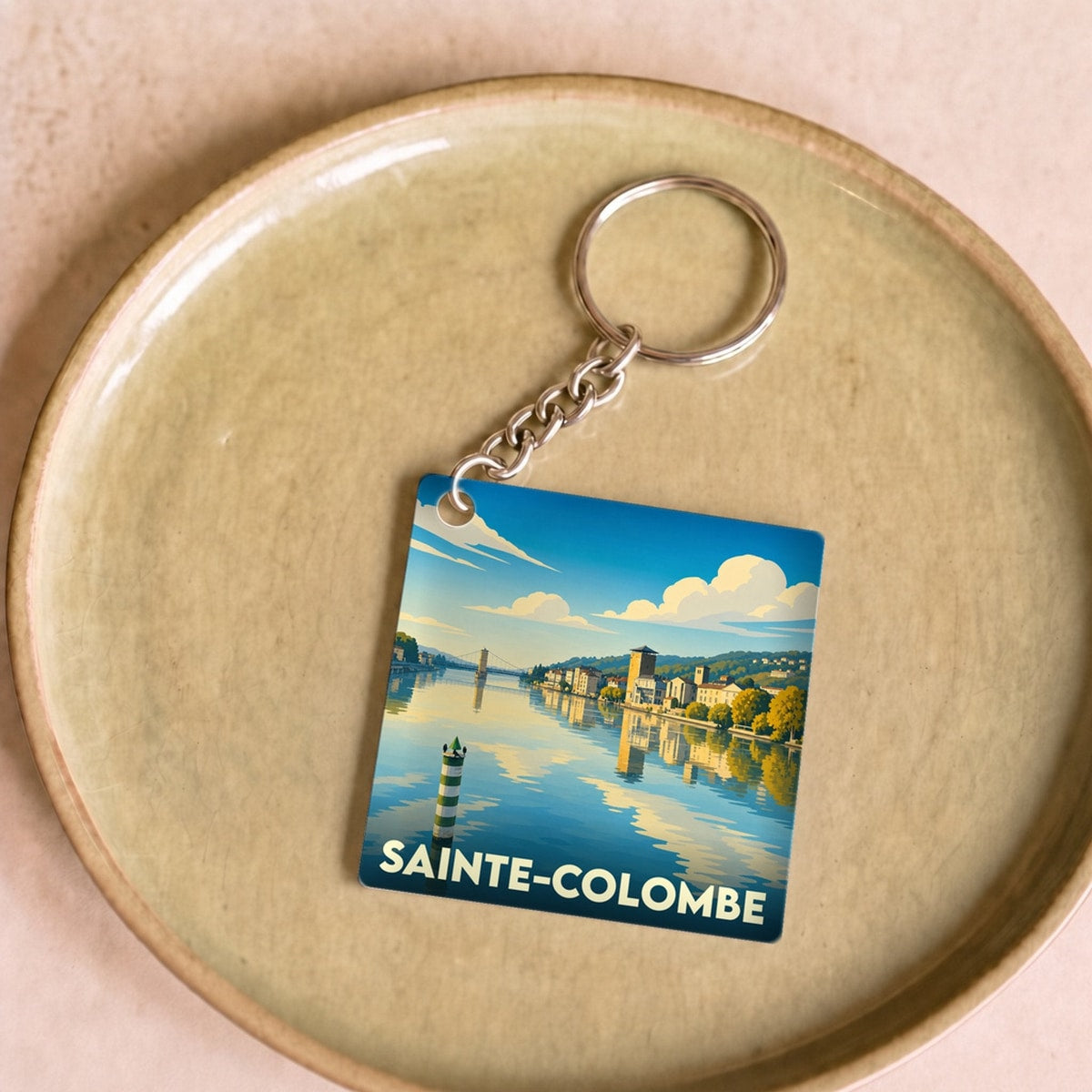 Porte-clés souvenir de la ville de Sainte-Colombe avec une illustration stylisée d'un paysage fluvial.
