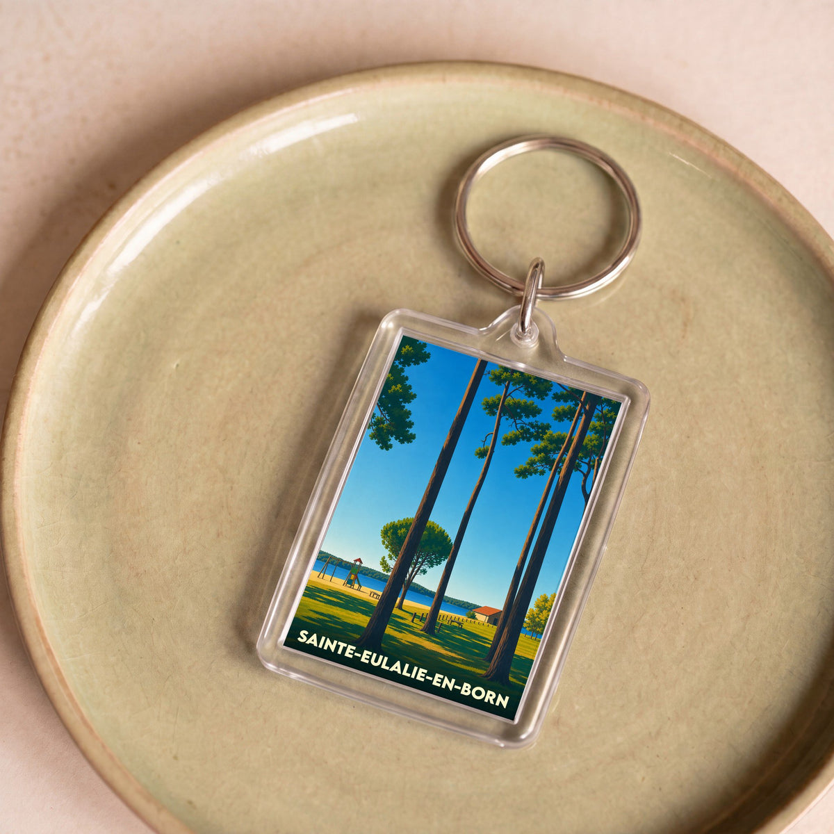 Porte-clés souvenir de la ville de Sainte-Eulalie-en-Born avec une illustration stylisée de pins au bord de l'eau.