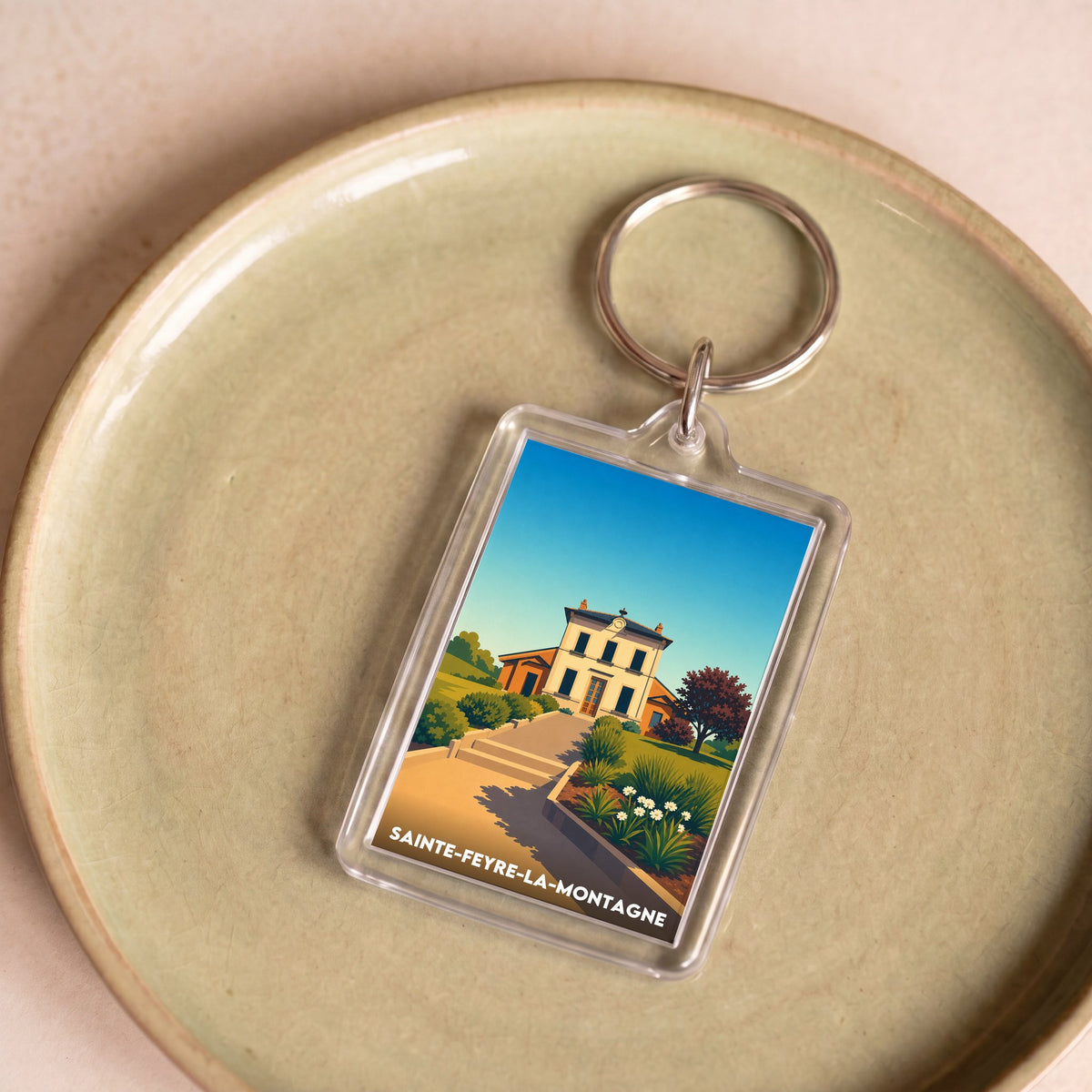 Porte-clés souvenir de la ville de Sainte-Feyre-la-Montagne avec une illustration stylisée.