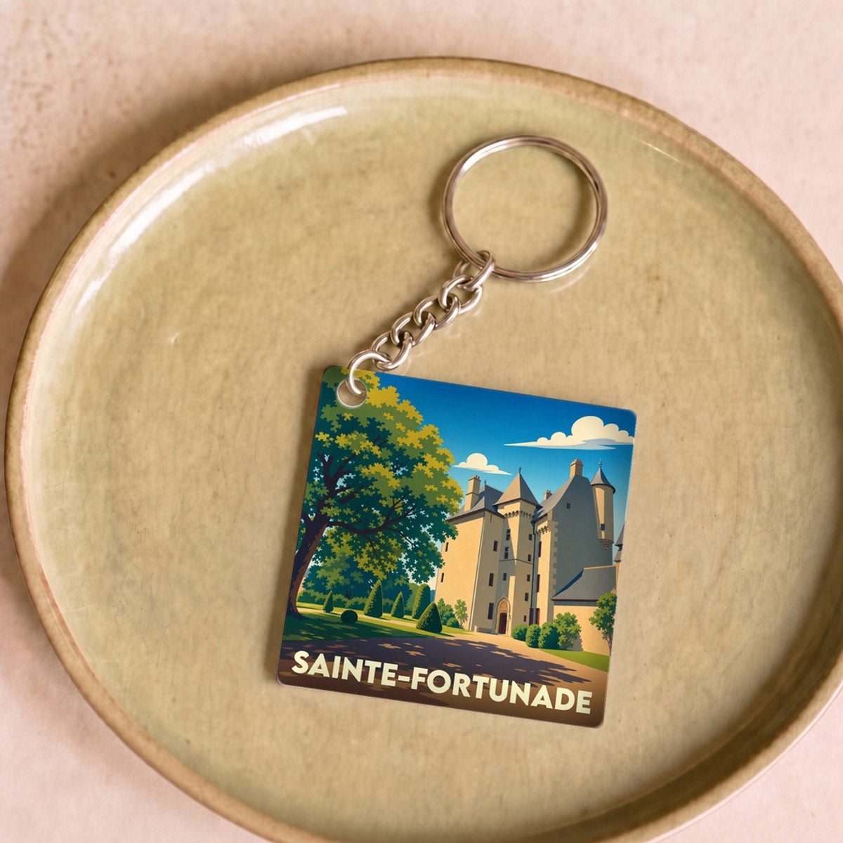 Porte-clés souvenir de la ville de Sainte-Fortunade avec une illustration stylisée de son château.