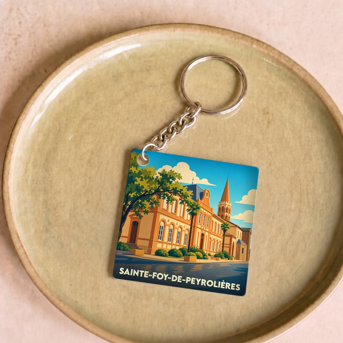 Porte-clés souvenir de la ville de Sainte-Foy-de-Peyrolières avec une illustration stylisée.