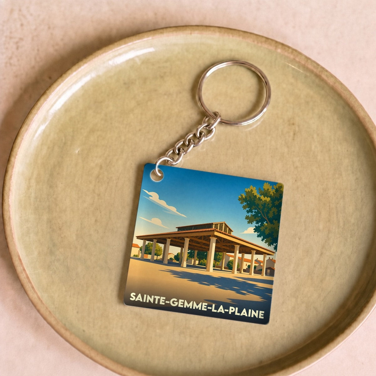 Porte-clés souvenir de la ville de Sainte-Gemme-la-Plaine avec une illustration stylisée de ses halles.