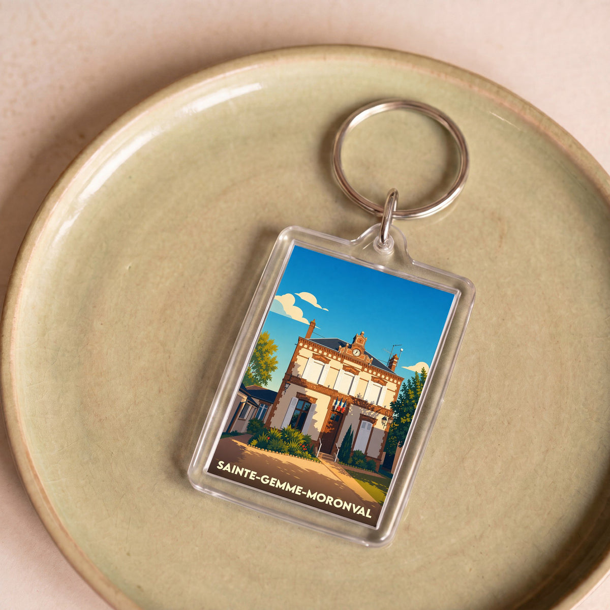 Porte-clés souvenir de la ville de Sainte-Gemme-Moronval avec une illustration stylisée de sa mairie.