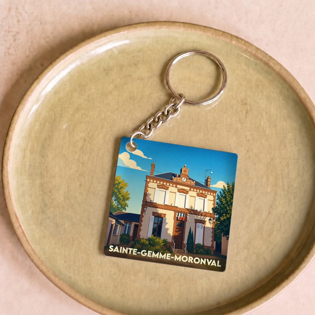 Porte-clés souvenir de la ville de Sainte-Gemme-Moronval avec une illustration stylisée de sa mairie.