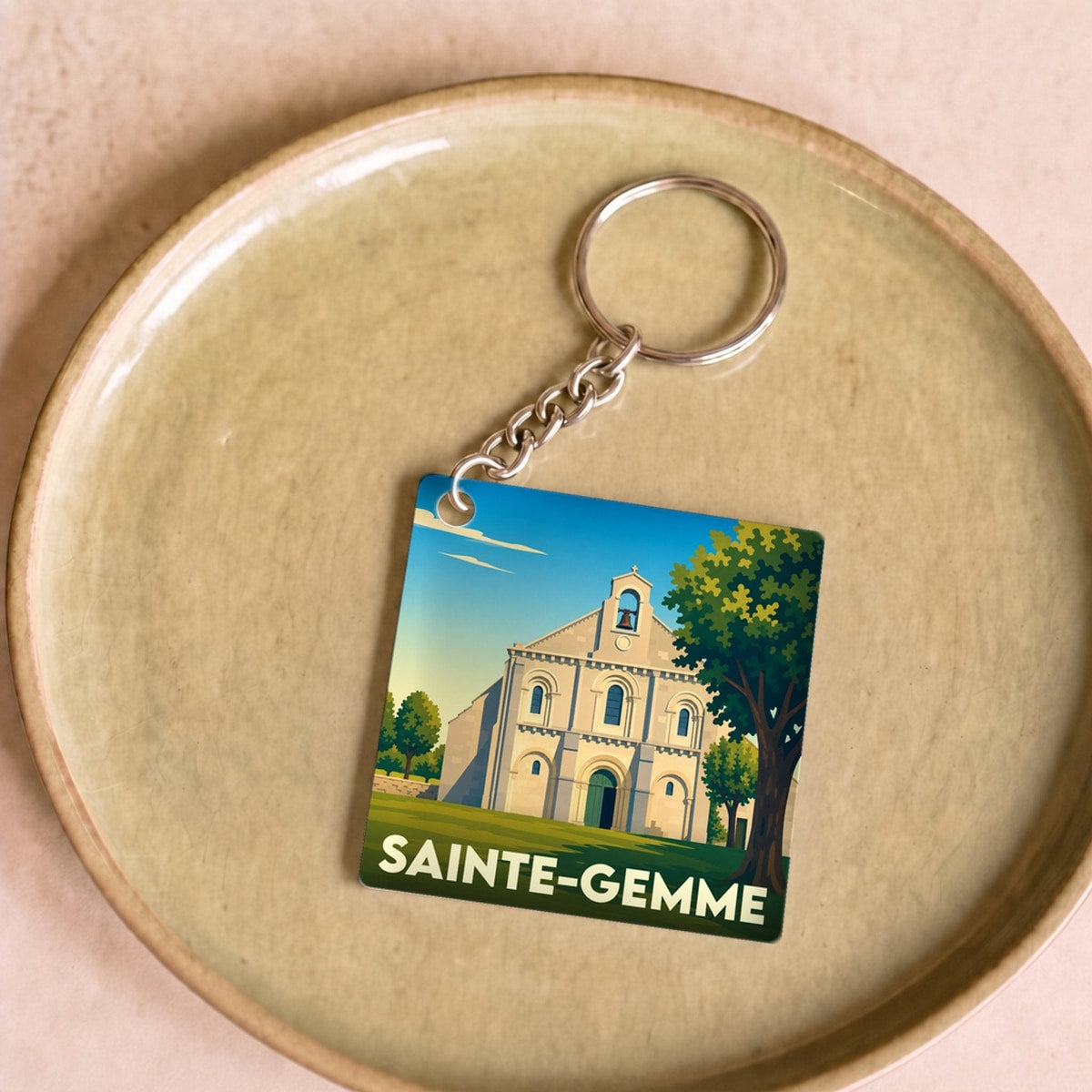 Porte-clés souvenir de la ville de Sainte-Gemme avec une illustration stylisée de son église.