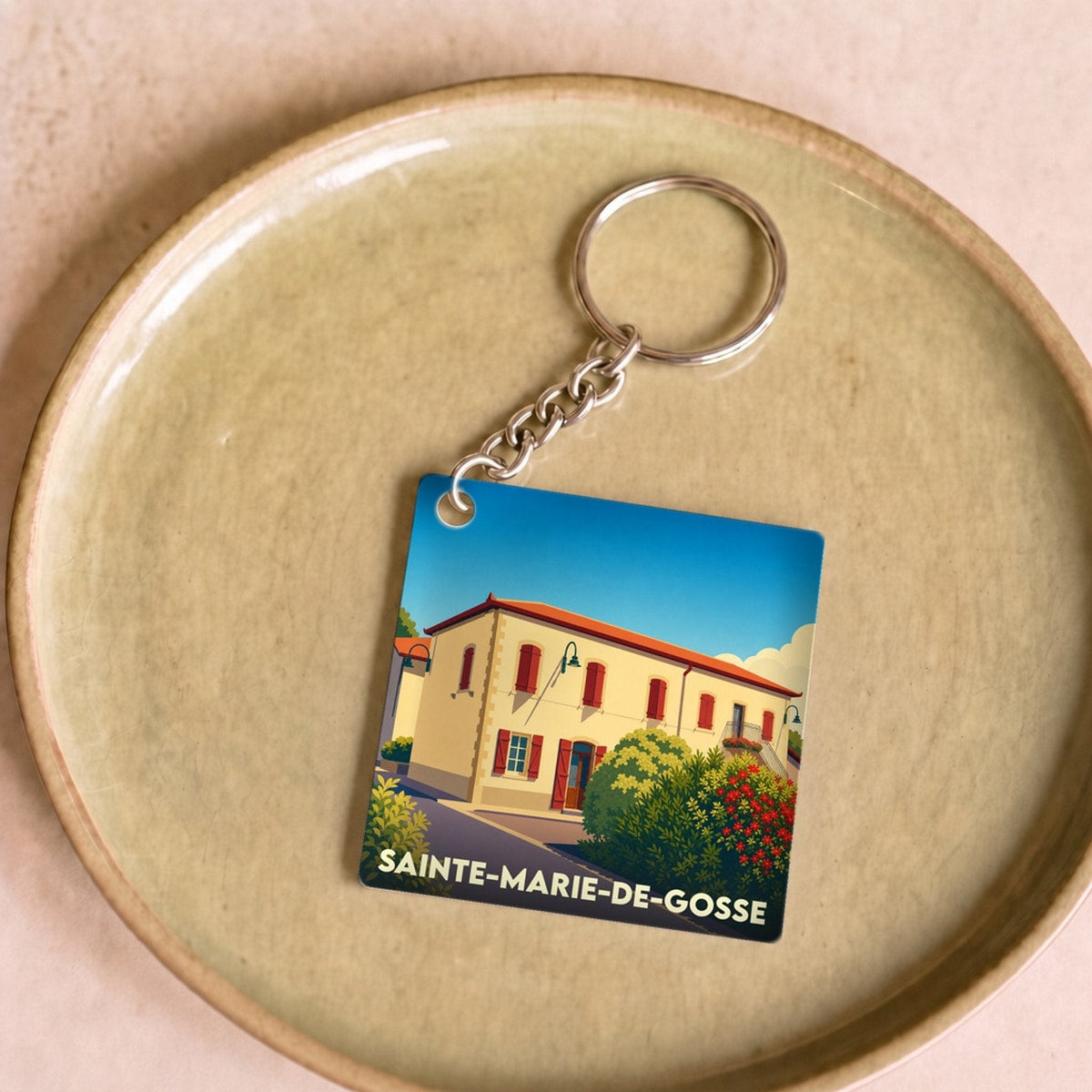 Porte-clés souvenir de la ville de Sainte-Marie-de-Gosse avec une illustration stylisée d'un bâtiment typique.