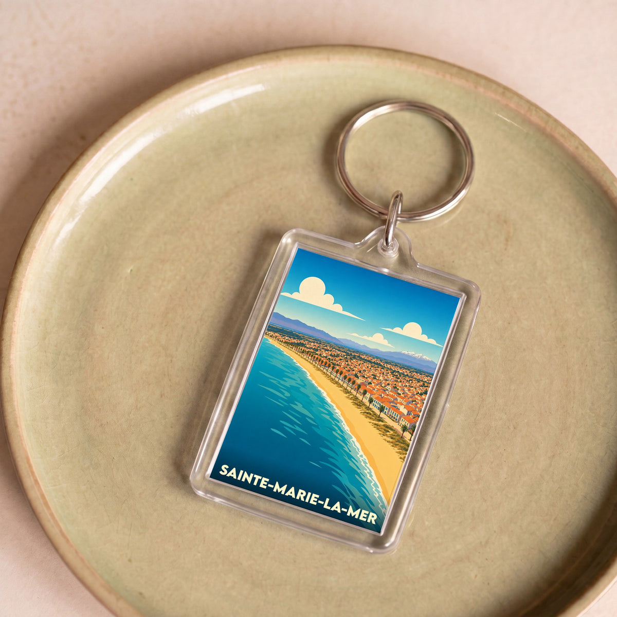 Porte-clés souvenir de la ville de Sainte-Marie-la-Mer avec une illustration stylisée du littoral.