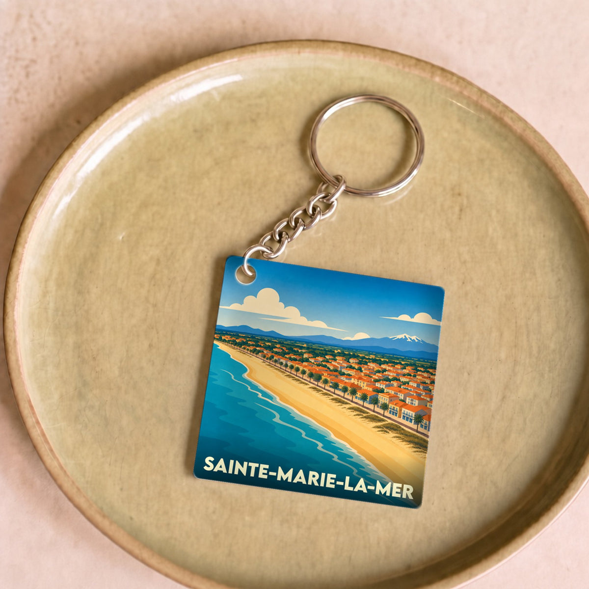 Porte-clés souvenir de la ville de Sainte-Marie-la-Mer avec une illustration stylisée du littoral.