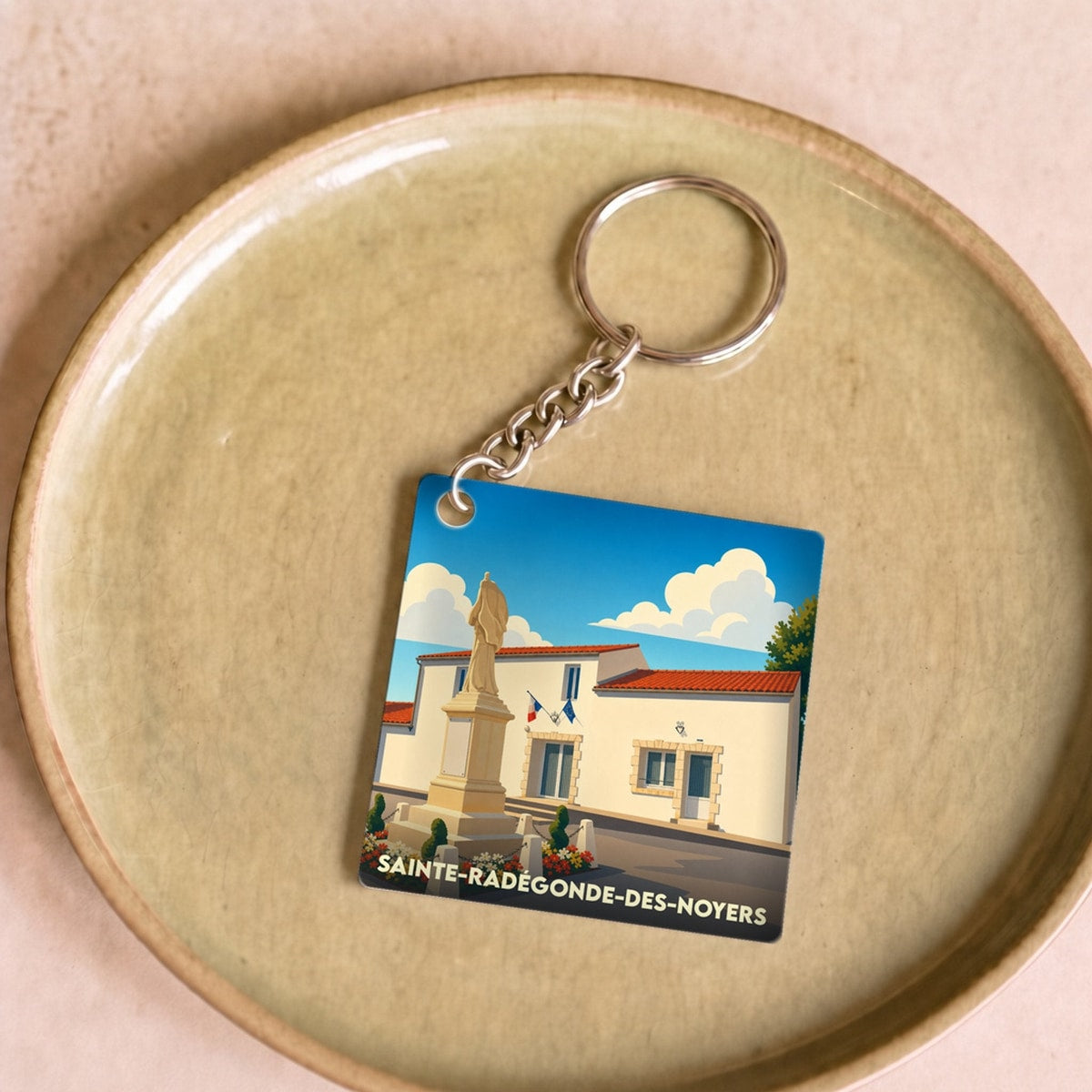 Porte-clés souvenir de la ville de Sainte-Radégonde-des-Noyers avec une illustration stylisée.