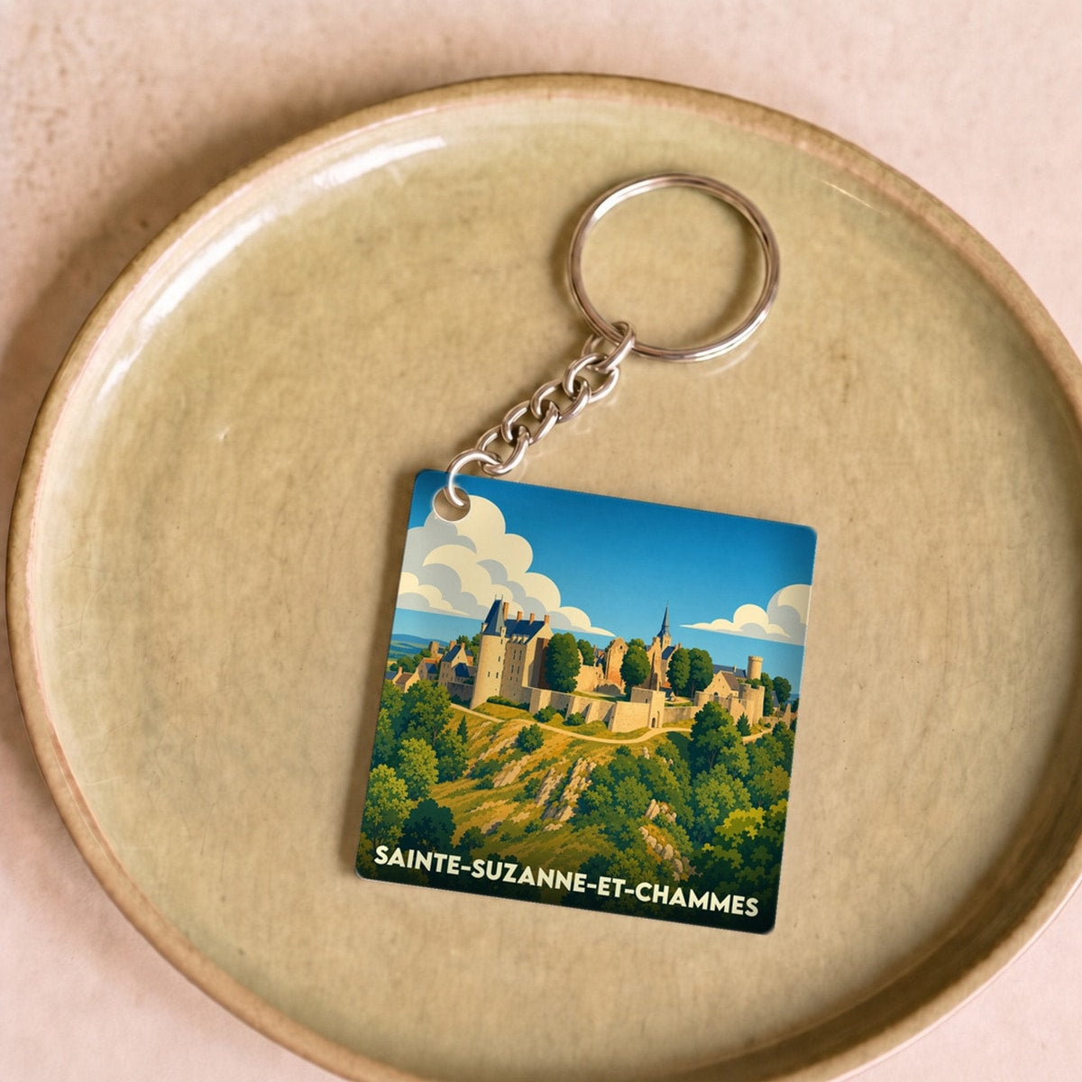 Porte-clés souvenir de la ville de Sainte-Suzanne-et-Chammes avec une illustration stylisée de son château médiéval.