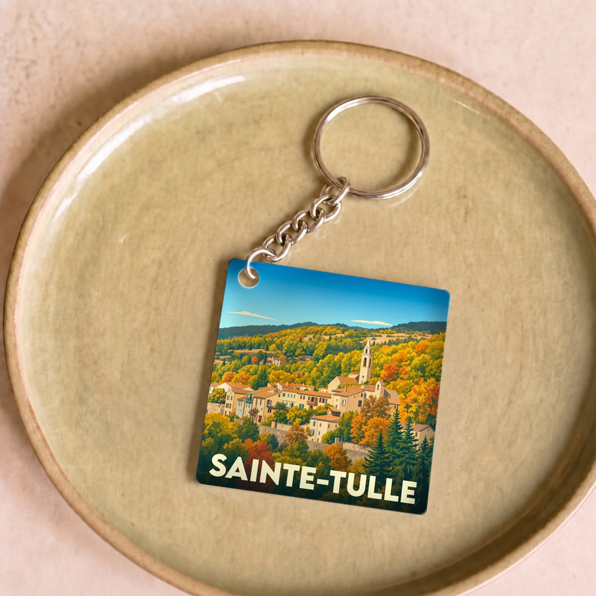 Porte-clés souvenir de la ville de Sainte-Tulle avec une illustration stylisée de son paysage vallonné.