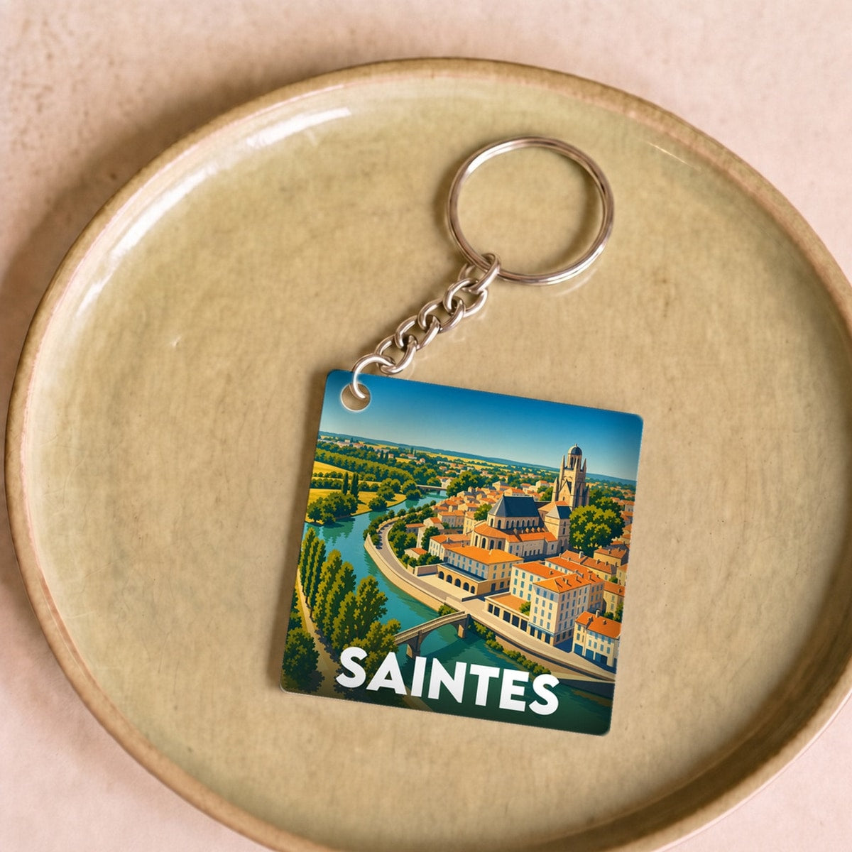 Porte-clés souvenir de la ville de Saintes avec une illustration stylisée.