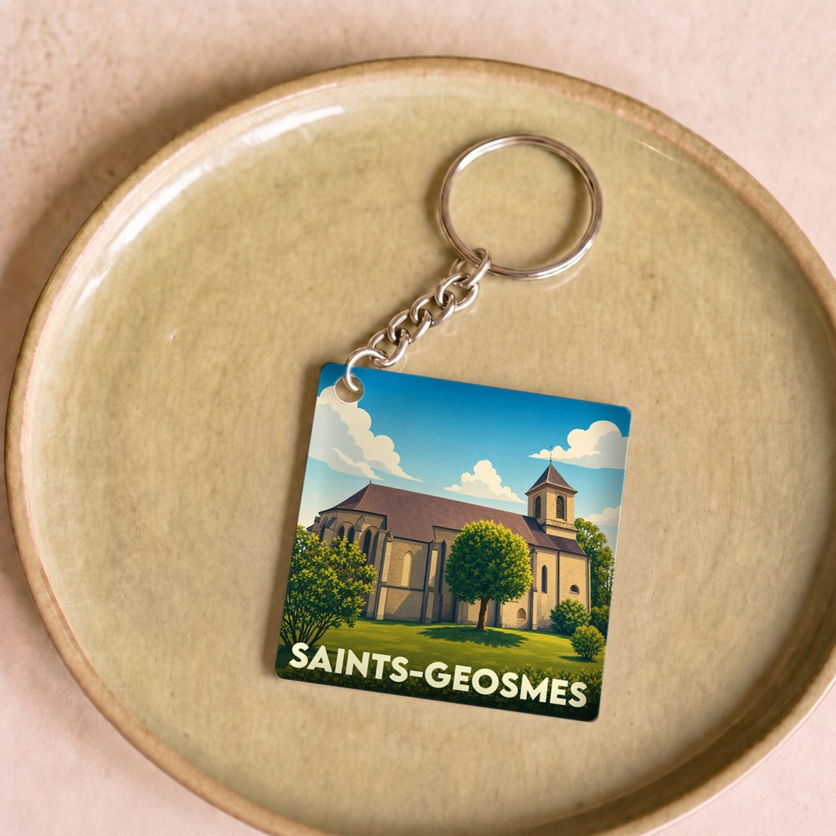 Porte-clés souvenir de la ville de Saints-Geosmes avec une illustration stylisée de son église.