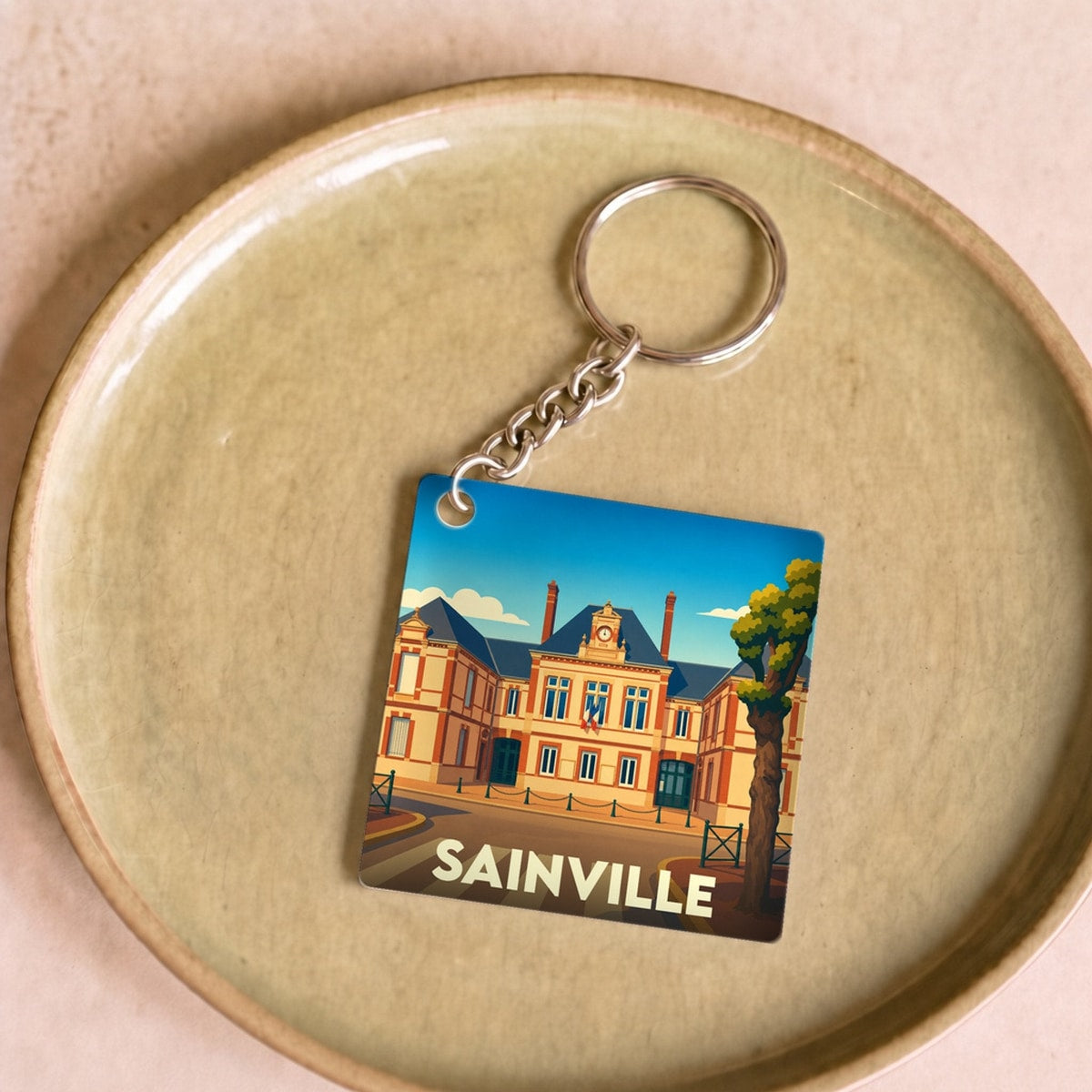 Porte-clés souvenir de la ville de Sainville avec une illustration stylisée.