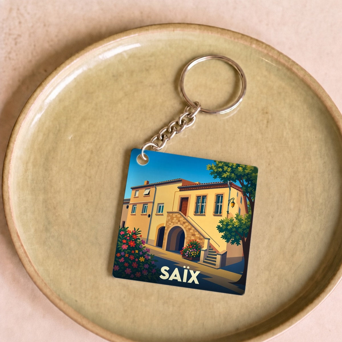 Porte-clés souvenir de la ville de Saïx avec une illustration stylisée d'une maison ensoleillée.