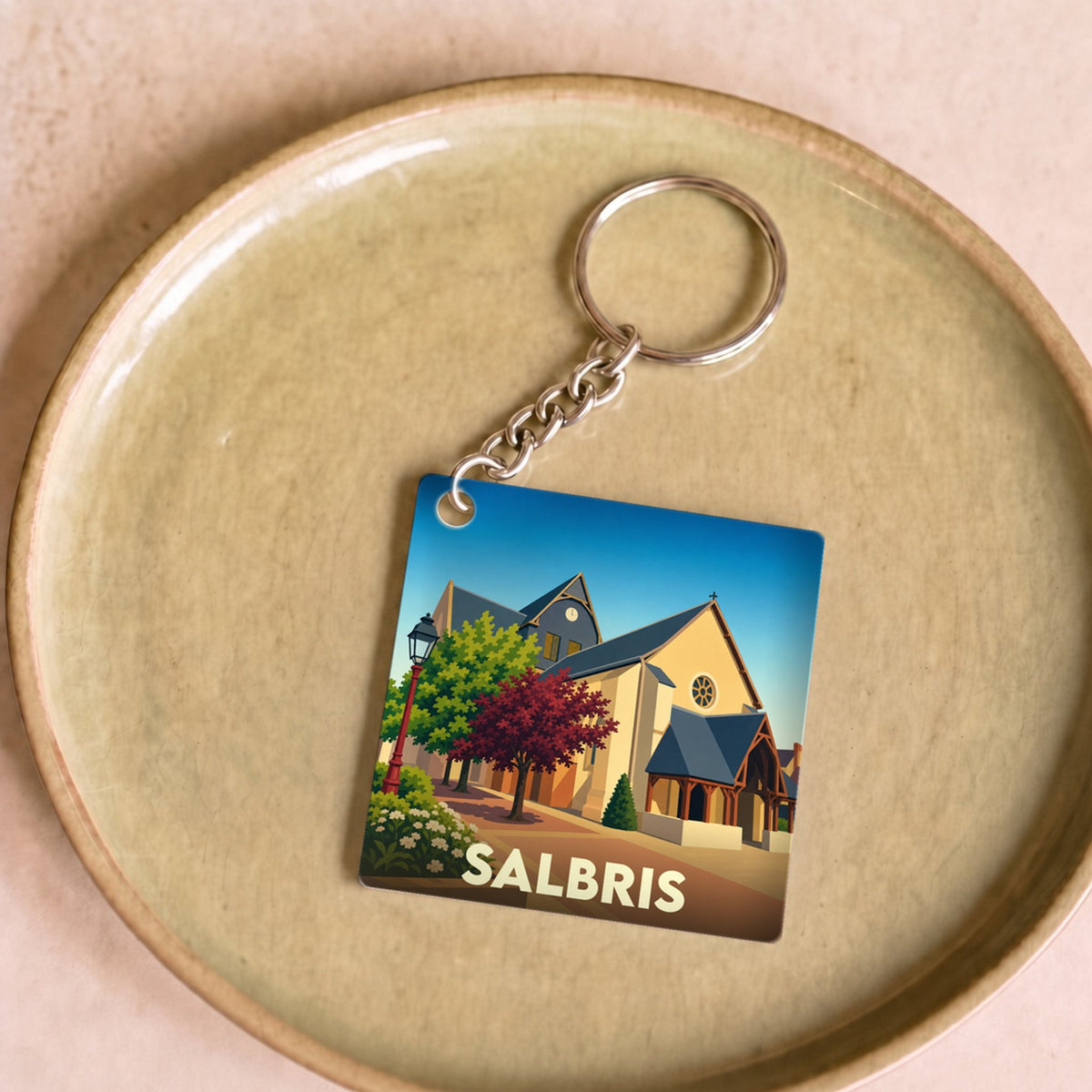 Porte-clés souvenir de la ville de Salbris avec une illustration stylisée d'une église et d'un paysage urbain.