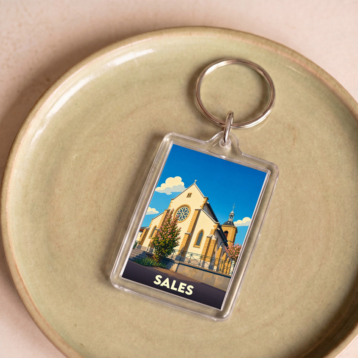 Porte-clés souvenir de la ville de Sales avec une illustration stylisée d'une église sous un ciel bleu.