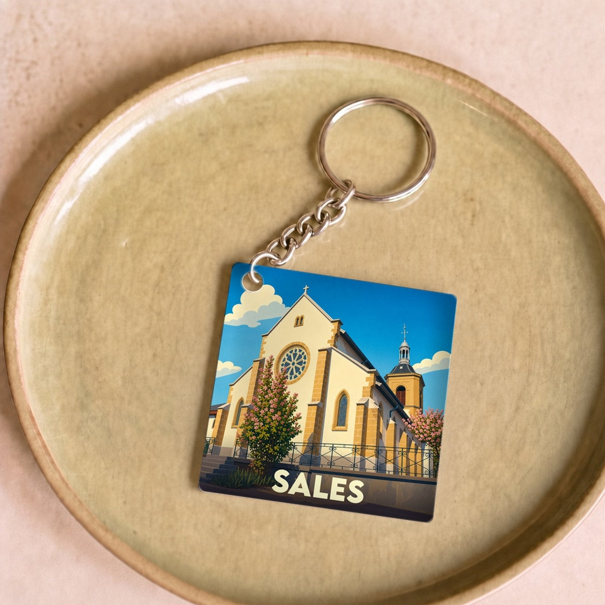 Porte-clés souvenir de la ville de Sales avec une illustration stylisée d'une église sous un ciel bleu.
