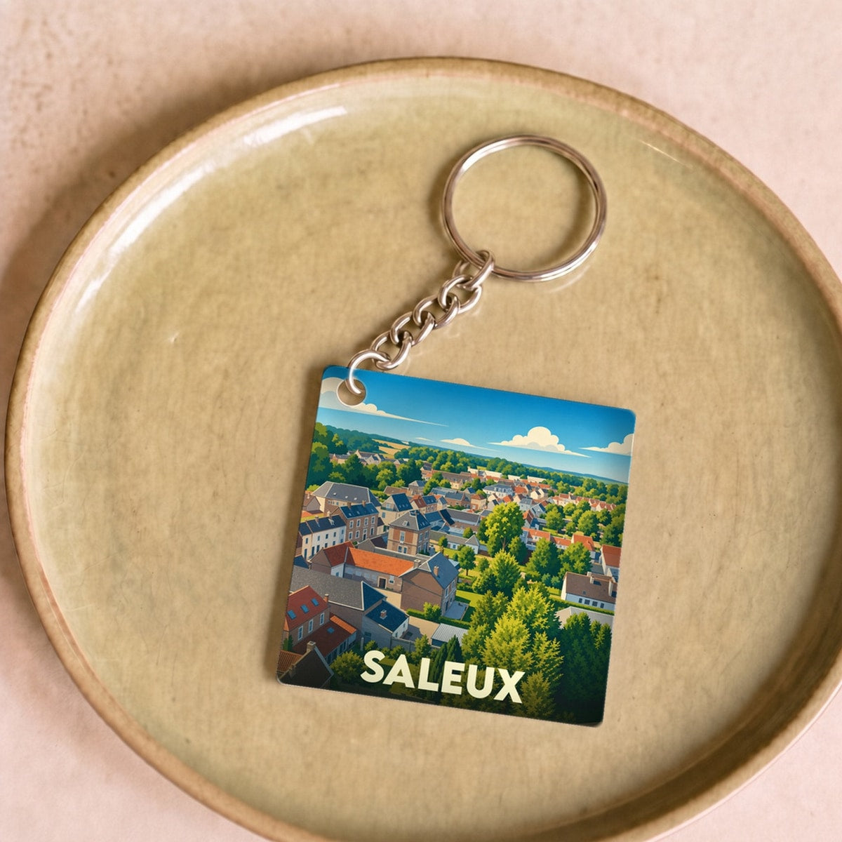 Porte-clés souvenir de la ville de Saleux avec une illustration stylisée d'un paysage urbain verdoyant.
