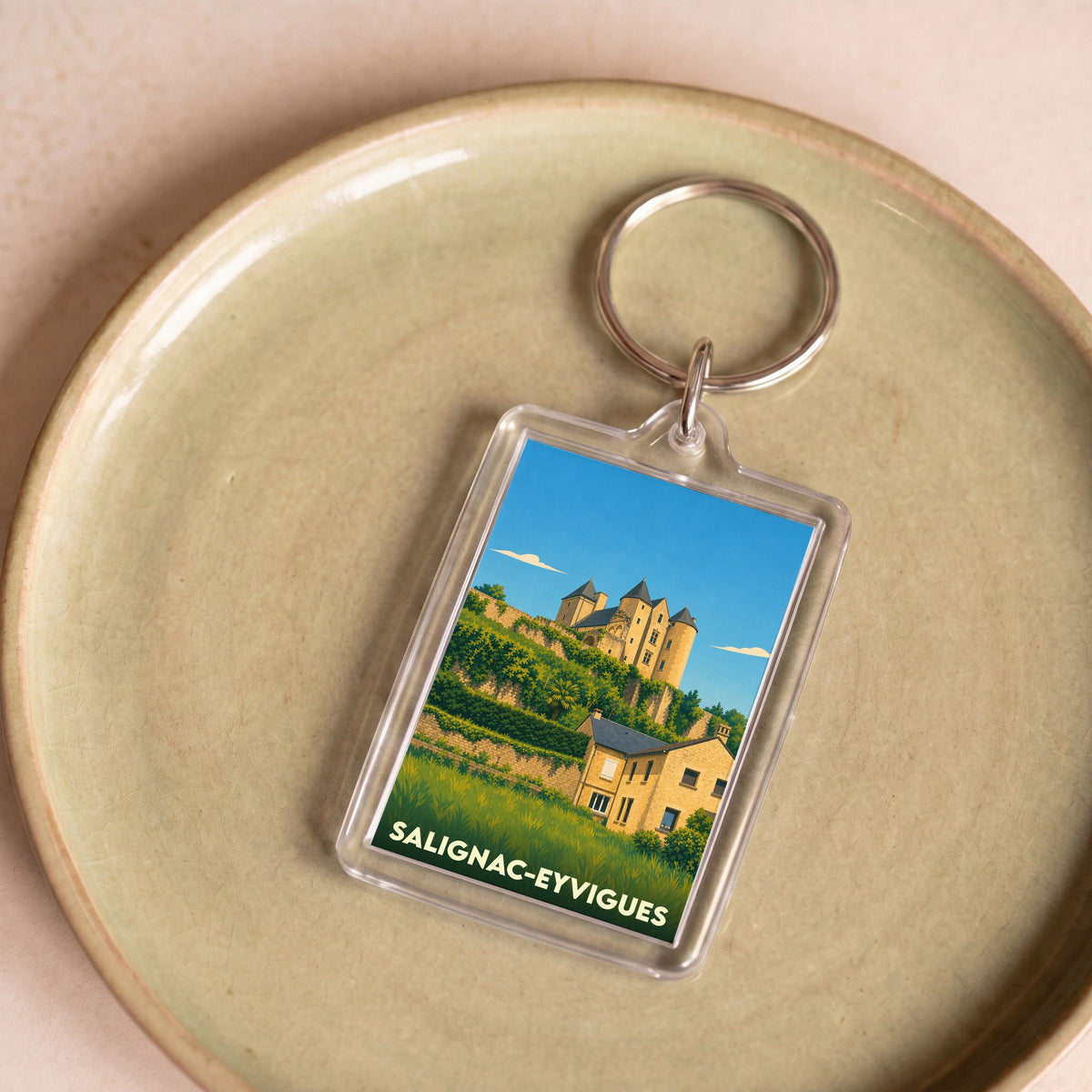 Porte-clés souvenir de la ville de Salignac-Eyvigues avec une illustration stylisée du château.