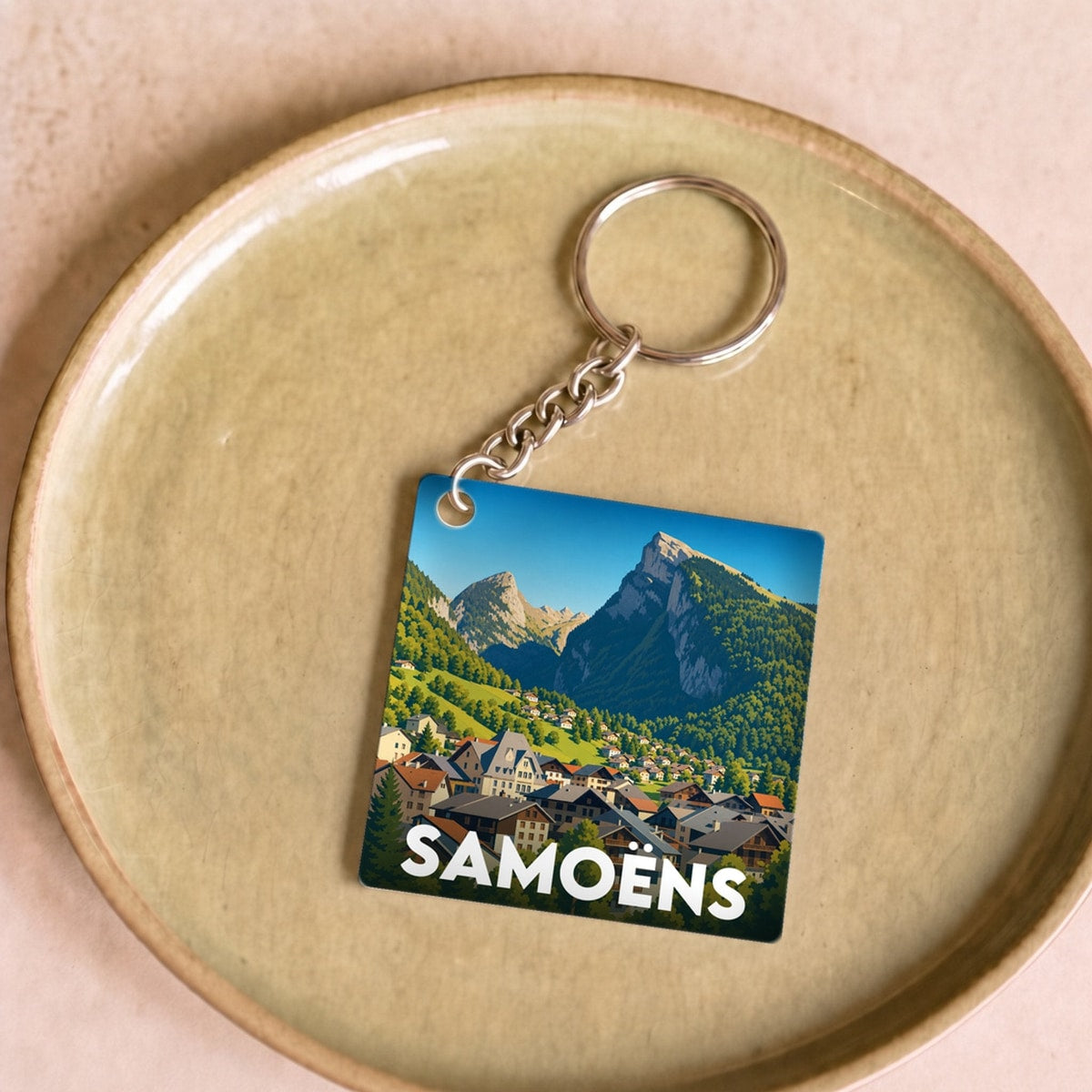 Porte-clés souvenir de la ville de Samoëns avec une illustration de paysage de montagne.