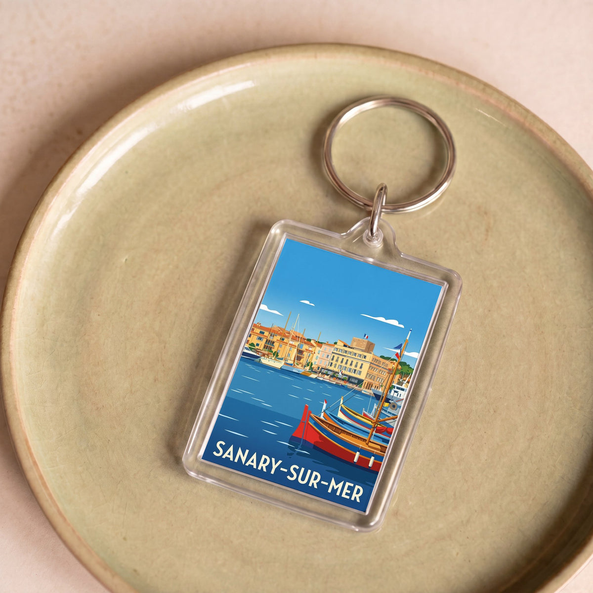 Porte-clés souvenir de la ville de Sanary-sur-Mer avec une illustration stylisée.