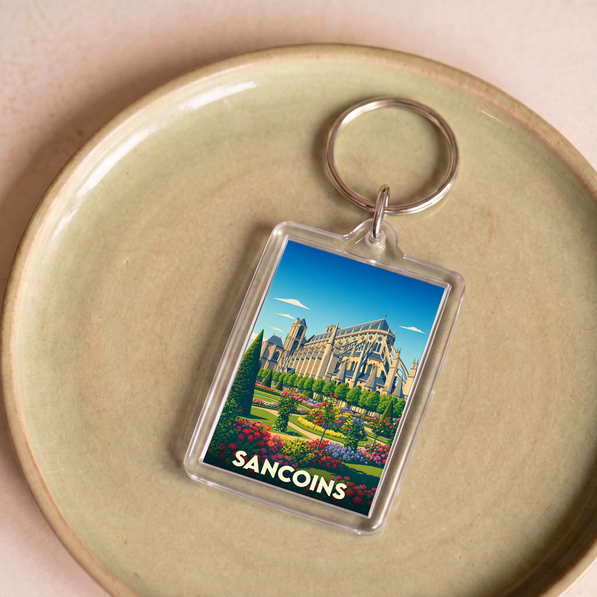 Porte-clés souvenir de la ville de Sancoins avec une illustration stylisée de son patrimoine et de ses jardins.