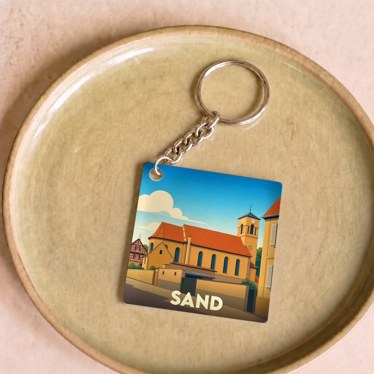 Porte-clés souvenir de la ville de Sand avec une illustration stylisée.