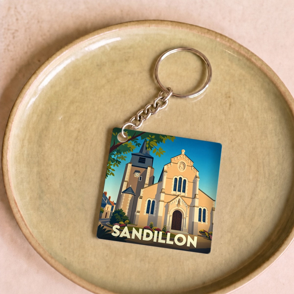 Porte-clés souvenir de la ville de Sandillon avec une illustration stylisée de son église.