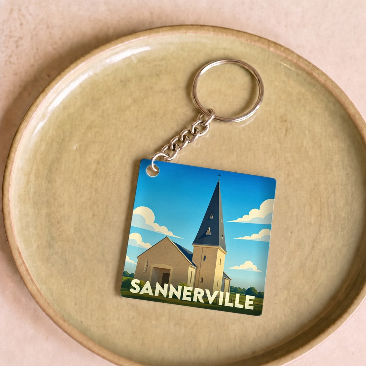 Porte-clés souvenir de la ville de Sannerville avec une illustration stylisée de son église.