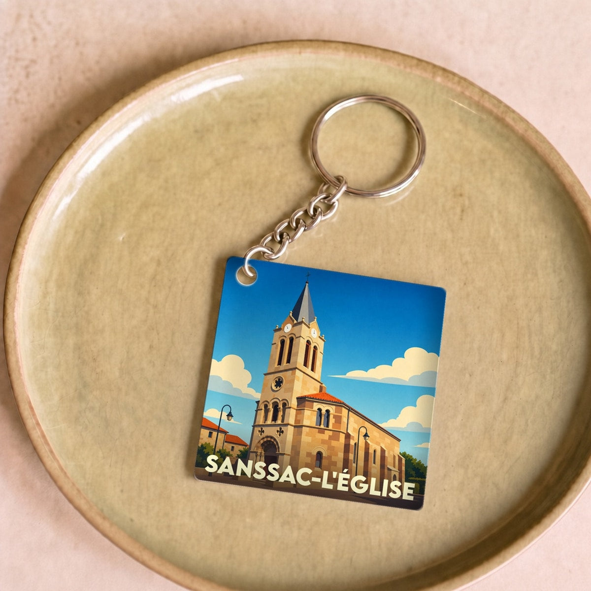 Porte-clés souvenir de la ville de Sanssac-l'Église avec une illustration stylisée.