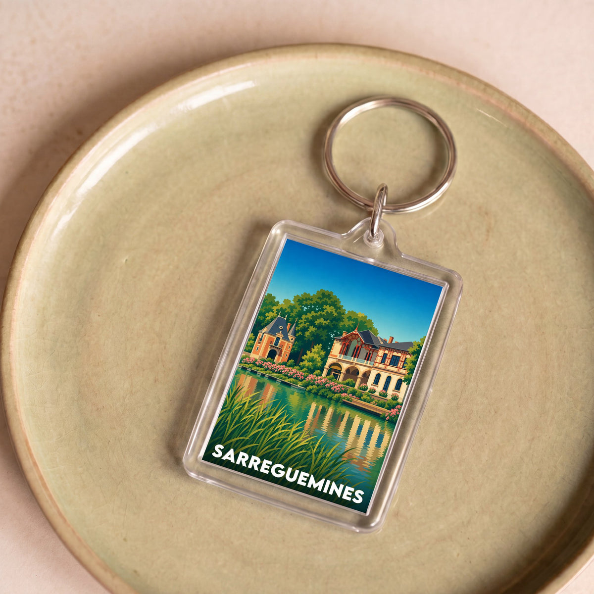 Porte-clés souvenir de la ville de Sarreguemines avec une illustration stylisée.