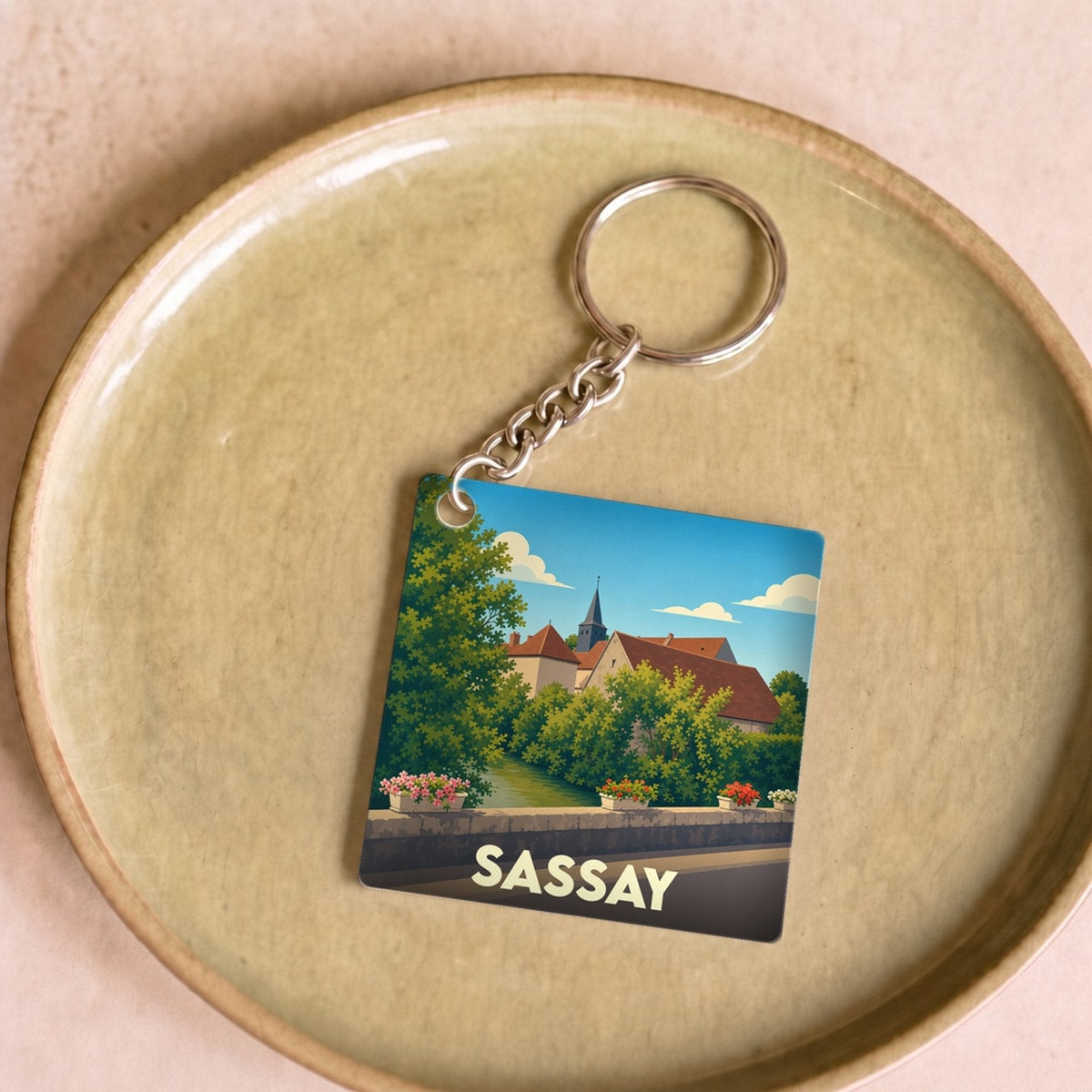 Porte-clés souvenir de la ville de Sassay avec une illustration stylisée d'un paysage urbain.