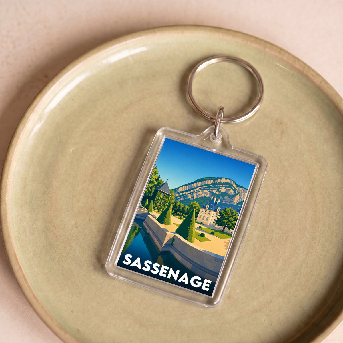 Porte-clés souvenir de la ville de Sassenage avec une illustration stylisée.