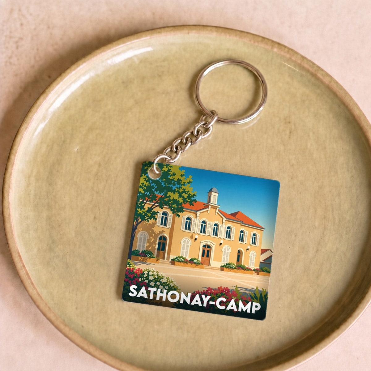 Porte-clés souvenir de la ville de Sathonay-Camp avec une illustration stylisée de sa mairie.