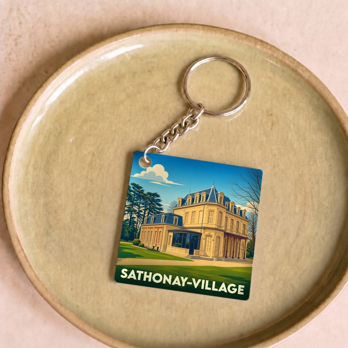 Porte-clés souvenir de Sathonay-Village avec une illustration stylisée d'un château sous un ciel bleu.